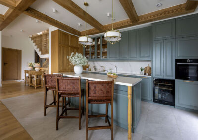 kuchnia z wyspą i wysokimi krzesłami z ciemnego drewna i eleganckimi meblami w kolorze przygaszonego błękitu