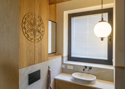 lazienka w naturalnym drewnie z ornamentem w stylu zakopianskim, z toaleta oraz zlew