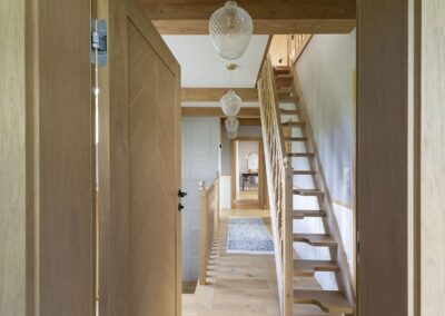 Widok na korytarz ze schodami na poddasze, wszystko w naturalnych kolorach drewna