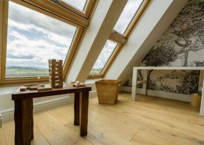 Pokój dziecięcy ze stołem i grami. W tle okno z widokiem. Ściana wyłożona elegancką czarno-białą tapetą z drzewami