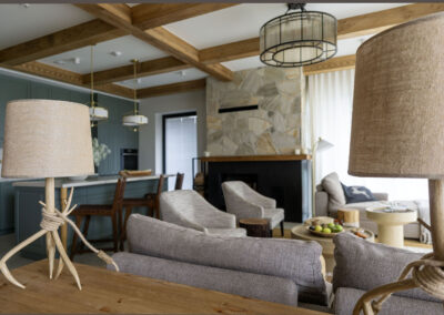 salon z kuchnią z zestawem wypoczynkwym w kolorze szarym, kominek oraz elegancka lampa wykonana z gałęzi