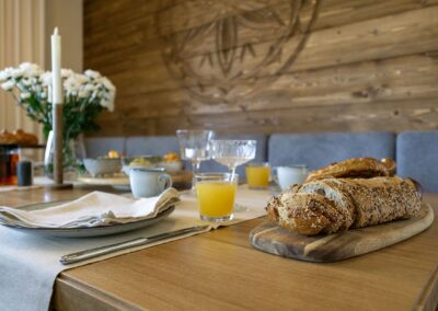 Stół nakryty do śniadania ze świeżym chlebem, zokiem pomarańczowym i bukietem świeżych kwiatów