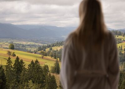 na pierwszym planie kobieta stojąca tyłem w patrzona w pejzaż górski