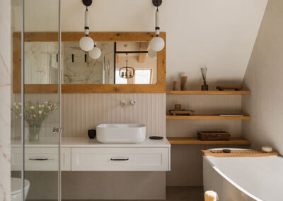 jasna łazienka z poziomy lustrem, białą umywalką, wanną i drewnianymi wykończeniami