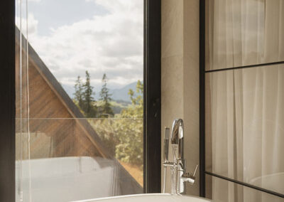 wanna przy oknie z widokiem na góry i sąsiedni dom