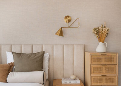 sypialnia z łóżkiem w białych i szatych kolorach, zagłówkiem z miękkiego materiału i szafką z jasnego drewna